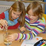 Zwei Schülerinnen beobachten unterschiedliche Brechungsindizes in Öl und Wasser