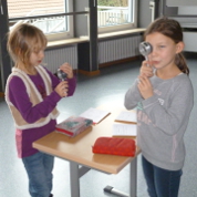 Zwei Schülerinnen experimentieren mit verschiedenen Arten von Linsen.
