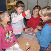 Eine Gruppe von Schülerinnen und Schülern baut eine Sammellinse aus einem mit Wasser gefüllten Luftballon.