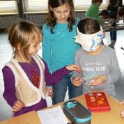 Drei Schülerinnen ertasten an Hand der Form die Art einer Linse.