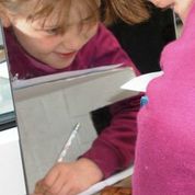 Eine Schülerin zeichnet während sie das Gezeichnete nur im Spiegel beobachtet.